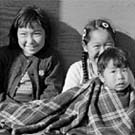 Photograph of four Inuit children sitting together on the ground, Resolute Bay (Qausuittuq), Nunavut, September 1959