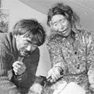 Photograph of an Inuit couple sitting in a tent. The woman is pouring water from a kettle into the man's tea cup, Eastern Arctic region, Nunavut, 1947