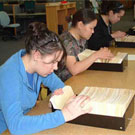 Photograph of students from Nunavut Sivuniksavut Training Program seaching the card catalogues at Library and Archives Canada, Ottawa, November 2004. Left to right: Nadia Mike-Dulmage and Jennie Soucie, both from Iqaluit (formerly Frobisher Bay), and Annie Aningmiuq of Pangnirtung (Pangnirtuuq)