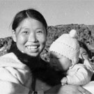 Photograph of the late Timothy Ottochie (left), husband of Aukshuali (centre) who is holding her baby. Two Inuit woman are standing on the right, Cape Dorset (Kinngait), Nunavut, 1948