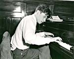 Photo de Glenn Gould jouant du piano, jambes croisées